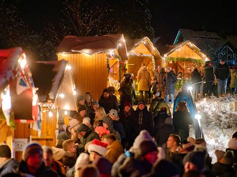 Zahlreiche Menschen schlendern entlang der beleuchteten Weihnachtsmarkthütten im Schlossgarten.