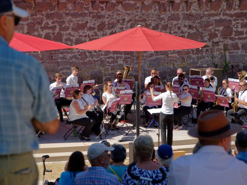 Dirigentin Lisa Moll und die Stadtkapelle beim Konzert vor der Sandsteinmauer des Schlosses.