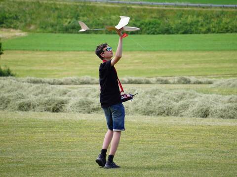 Ein Jugendlicher hält einen Modellflieger in die Luft.