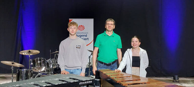 Florenz Körber, Musikschulleiter Dr. Gregor Daszko und Antonia Körber stehen hinter ihren Instrumenten vor einem Jugend-musiziert-Banner.
